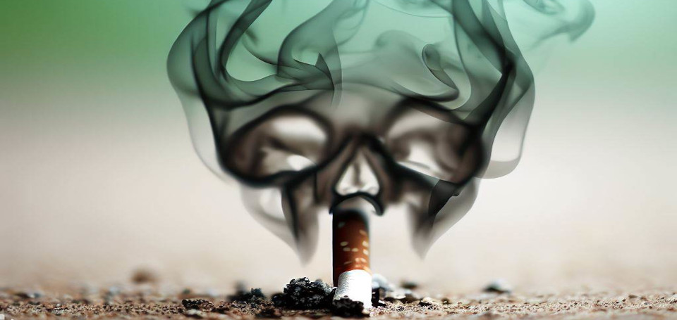 Une cigarette écrasée fume encore. La fumée ressemble à une tête de mort